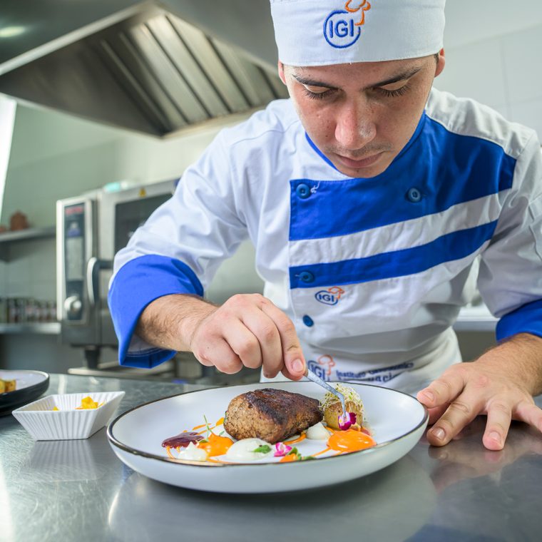 Chef trabajando en el emplatado de un plato en una cocina de IGI